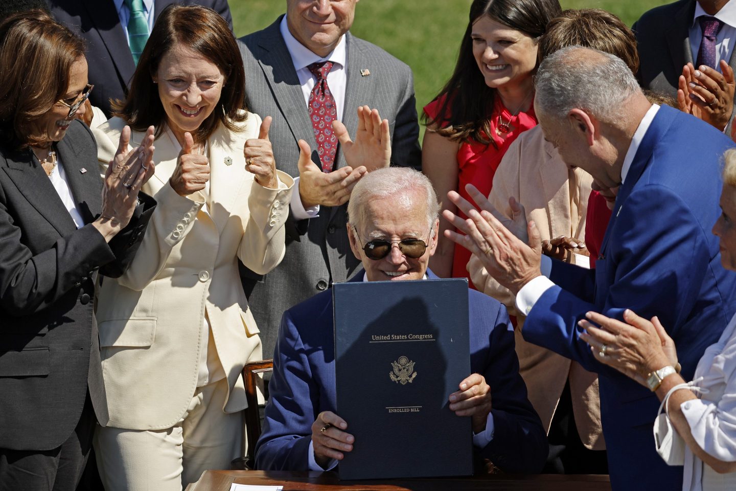 U.S. President Joe Biden holds up a signed copy of the CHIPS and Science Act surrounded by fellow politicians